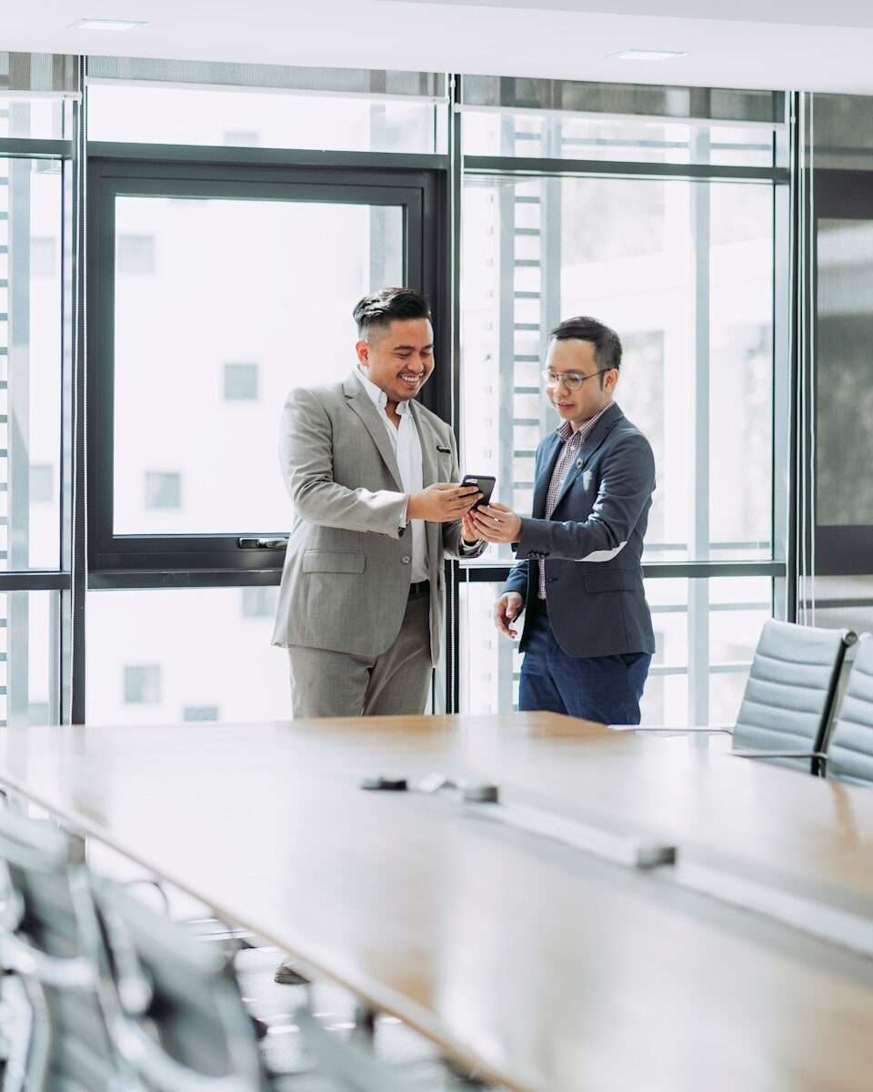 two businessmen looking at phone in office